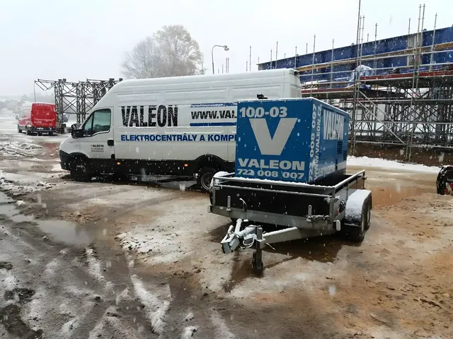 Centrála Valeon na přívěsu a dodávka Valeonu na zasněženém staveništi u lešení