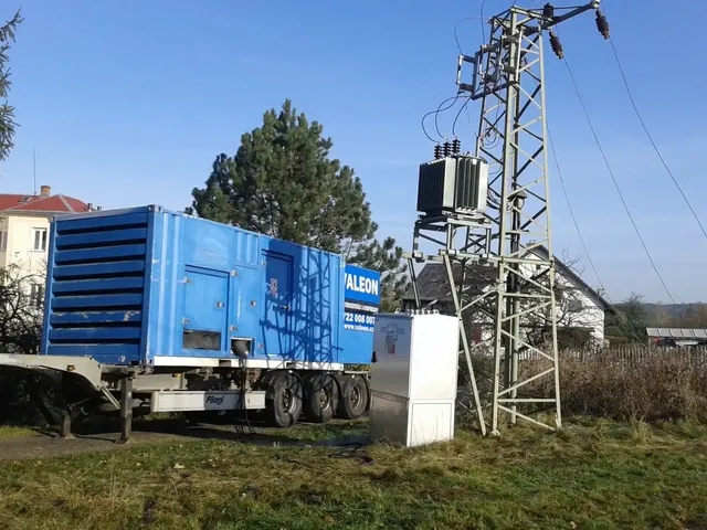 Kontejnerová centrála Valeon na návěsu vedle sloupové trafostanice na okraji obce